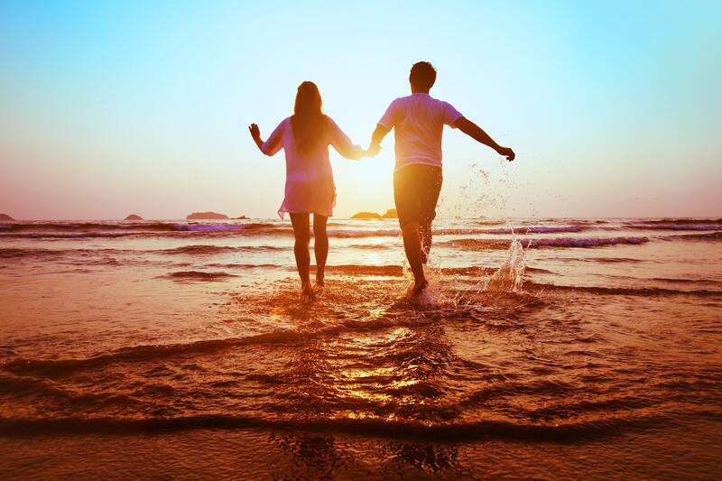 Couple holding hands, walking in the waves